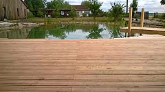 Schwimmteich (Badesee) mit Holz-Terrasse und -Steg, Einfassung, Ufer und Bepflanzung